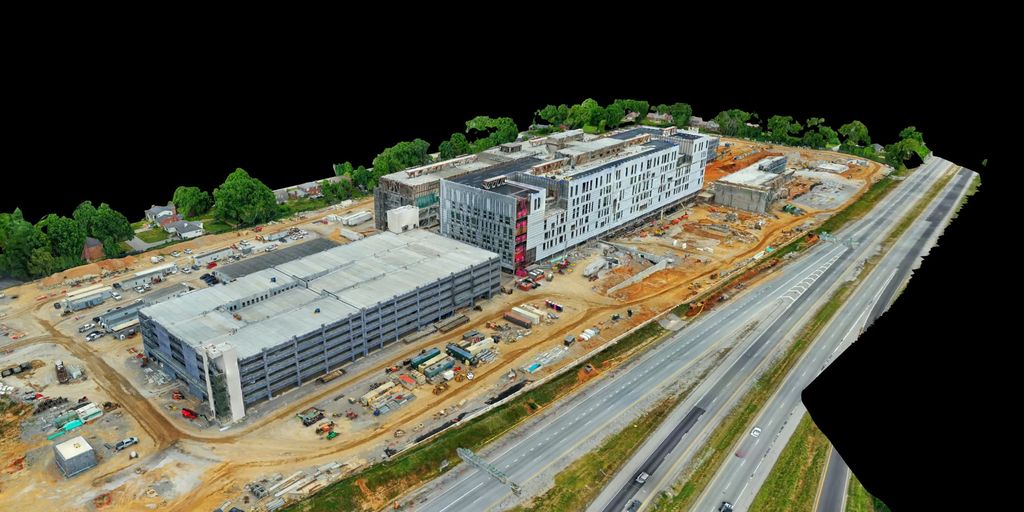 3D model of a construction site with a parking garage and multistory building beside an interstate