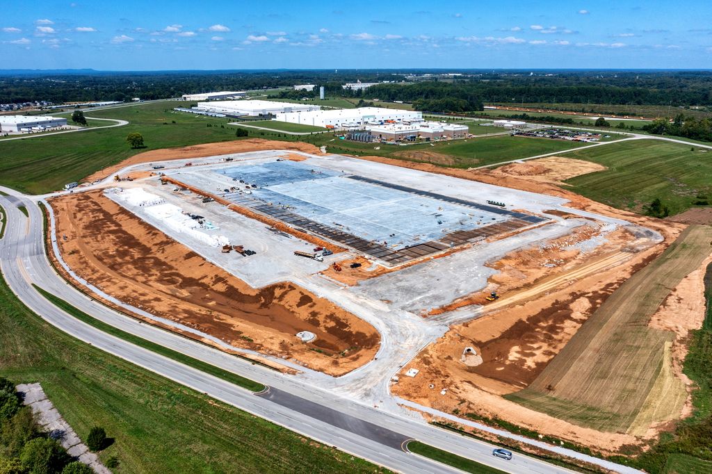 New building pad with a concrete slab and fresh red clay grading in Kentucky