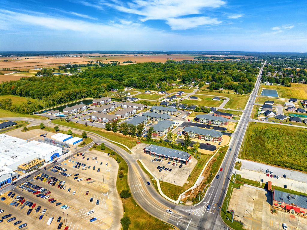 New Evansville development with a store parking lot, apartments and farmland beyond