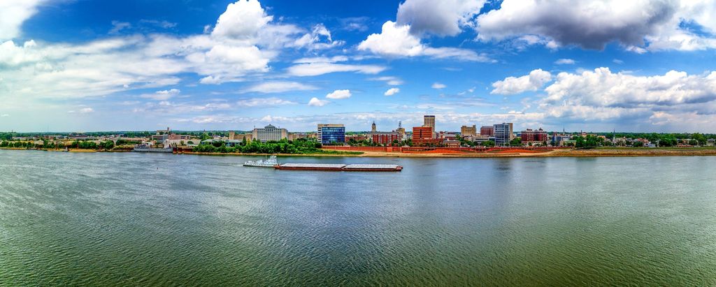 Evansville riverfront skyline across the Ohio River with a barge passing
