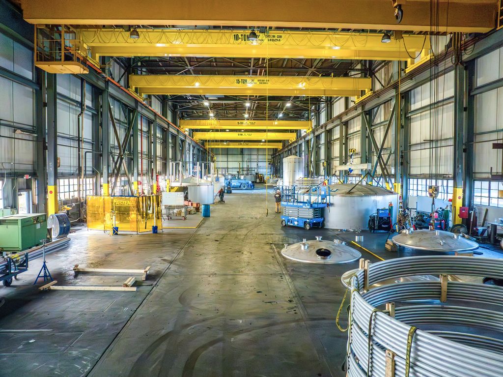 Long fabrication aisle under yellow bridge cranes with stainless tank parts