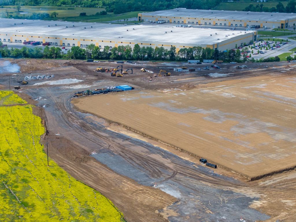 Graded building pad next to an existing distribution center and a yellow field