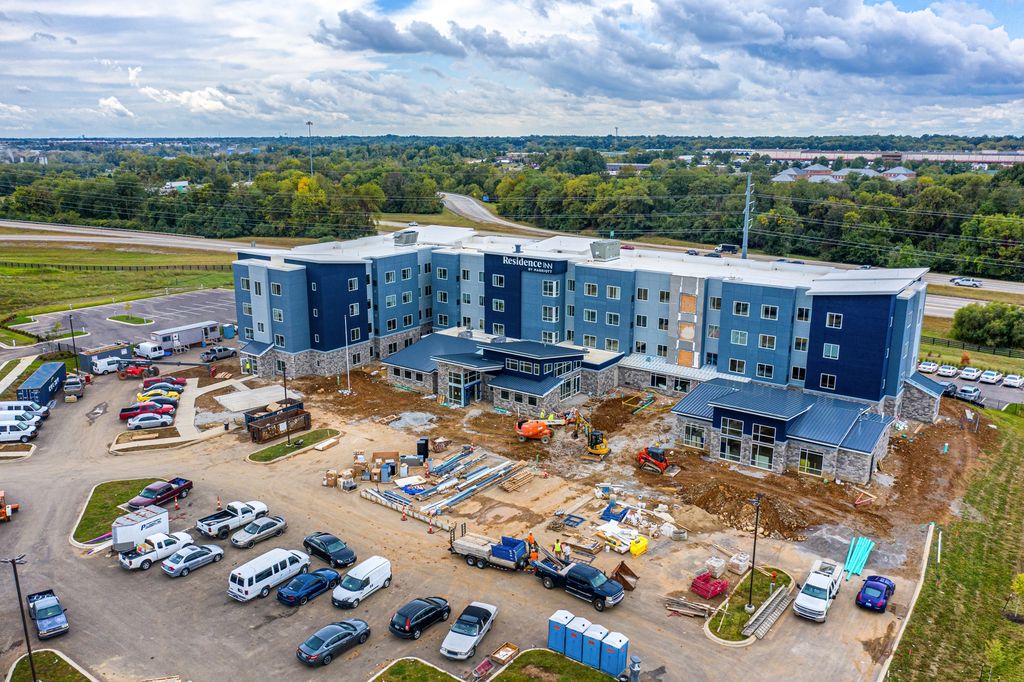 Four-story hotel under construction with crews and equipment in the parking lot