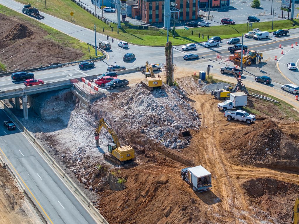 Excavators breaking out an overpass abutment at I-264 and U.S. 42 as traffic passes above