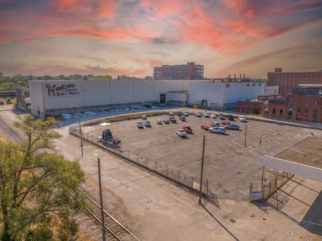 Long industrial plant and parking lot under a pink sunset sky