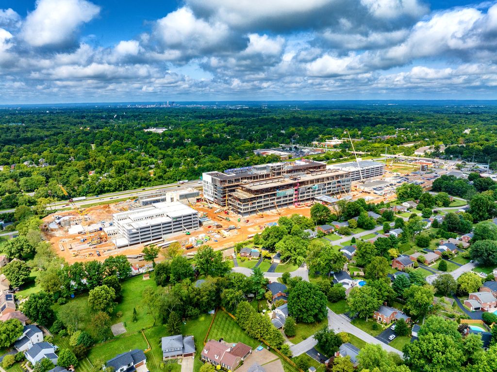 Large multistory building complex under construction beside a leafy neighborhood