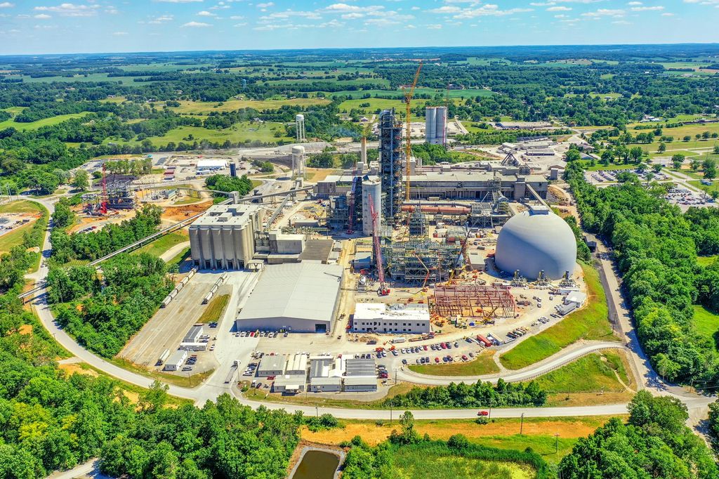 Industrial plant with a tower, silos and a white dome surrounded by woodland