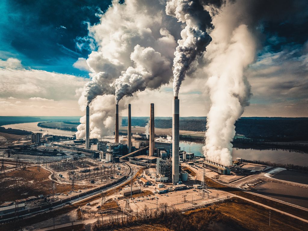 Power plant smokestacks and cooling steam under a dramatic sky