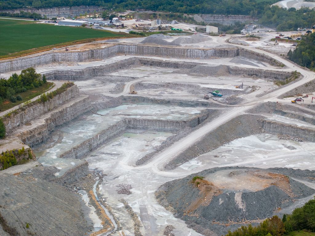 Deep benched quarry pit with switchback haul roads and stockpiles, seen from above