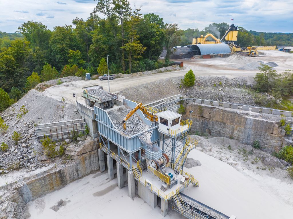 Primary crusher station with an excavator feeding rock at the edge of a quarry pit