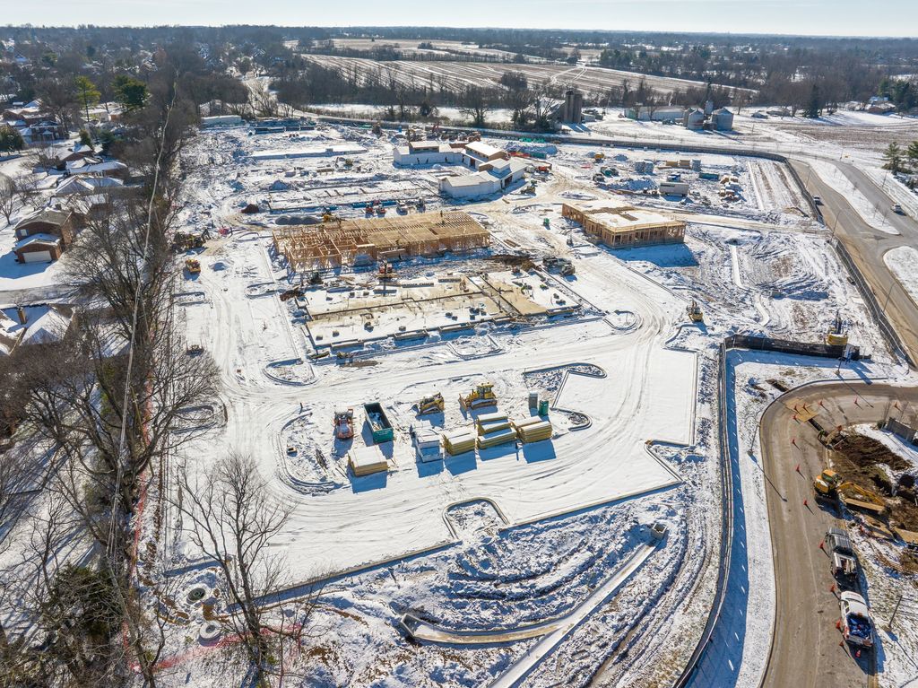 Snowy building site with wood-framed structures and a curved access road