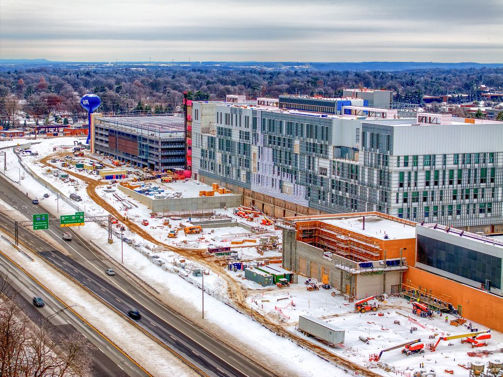 Multistory hospital building under construction beside a snowy interstate